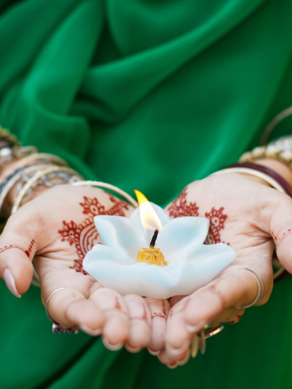 Beautiful woman in traditional Muslim Indian wedding green sari Beautiful woman in traditional Muslim Indian wedding green sari dress hands with henna tattoo mehndi pattern jewelry and bracelets hold burning lotus candle Summer culture festival celebration concept